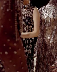 Seen backstage at the Alexander McQueen Autumn/Winter 2019 show: A tulle tunic finished with glass stones, metal thread, beads and bullion embroidery and a silver heddle embroidered dress.