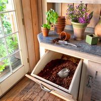 A handy tip-out bin keeps potting soil at the ready in a multi-use garden house | Photo: Mark Lohman | thisoldhouse.com