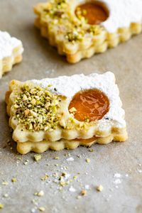 Soft and sweet Linzer Tart Cookies! Holiday almond sugar cookies, apricot jam, that are decorated with powdered sugar and pistachios.