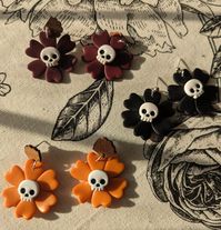 Skully the skeleton flower Skully is handcrafted in small batches using polymer clay. Three color variations  of Black, Orange, or crimson flower with a white skull center. Lightweight dangle earrings for fall.  Earring findings: Sterling silver ball or wood post, with a 7 mm sterling silver jump ring. I only use rubber backings for all my pieces, but I can switch them out for stainless steel or sterling silver options upon request.  Polymer clay is durable and cured to be flexible BUT it needs