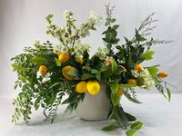 This is a whimsical design of lemons, white cherry blooms, white snowballs, mini boxwood, lemon branches, ferns, lavender berries, green ruscus, hint of lime, and a mix of different greenery. The arrangement is designed on all sides with a beautiful hanging lemon branch and lemon. The whimsical design can be used as a centerpiece or to add cheer to your kitchen island.  Length: 29 Inches, Width: 14 Inches, Height: 24 Inches Thank you for viewing S&B Blumen Design shop. Please contact us with any