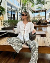 Get inspired by this casual summer outfit! A white tie-front longsleeve blouse paired with stylish leopard print pants, elegant black shoes, and a Bottega Veneta bag. Perfect for a chic and effortless look. Pin now for your next fashion inspiration! #SummerOutfit #CasualChic #LeopardPrint #FashionInspo #WomensFashion