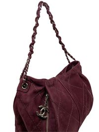 This Chanel Quilted Suede Darjeeling Hobo is beautifully crafted from burgundy diamond quilted suede. The bag features a chain link shoulder strap threaded with tonal suede and two exterior-front vertical zipper pockets, one with a signature Chanel ‘CC’ zipper pull closure. The top-center magnetic snap closure opens to a matching fabric lining with a large patch and zipper pocket. The signature 'CC' medallion on the front zip compartment adds a touch of the fashion house's sophistication. Condition: Very Good. Although a beautiful bag with life left in it, imperfections have developed throughout. The exterior burgundy suede has signs of wear and scuffing. The shoulder strap is in overall excellent condition with some scuffing on the suede. The silver-tone hardware shines bright with some f