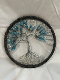 Wire tree in a metal ring. Beads on the tree and ring wrapped with cord