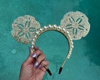 For all my mermaid girlies! These resin sand dollar mouse ears are neutral yet show stopping at the same time. The mouse ears headband is accented with 2 rows of oversized pearls, and the resin sand dollars sparkle with gold flecks and gold glitter. A perfect complement to any mermaid outfit or Ariel inspired look for the parks, these ears are mer-made for you :). Due to the handmade nature of my ears and the artistic quality of resin, each pair will vary slightly, making yours unique and just f