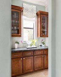 Cool-toned, brushed nickel finish cabinet pulls add a more up to date look to these traditional wood cabinets.