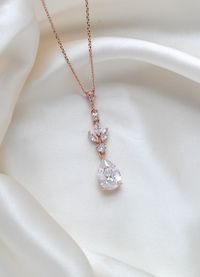 Dainty, feminine, and sweet brides will love this rose gold wedding jewelry set. The small crystals and the fashionable rose gold make these earrings and this fine necklace a marvelous way to accessorize a simple, yet feminine and elegant wedding gown. We recommend a ballgown with delicate details for the perfect pairing. PLEASE ALLOW APPROX 7 BUSINESS DAYS FOR COMPLETION BEFORE SHIPPING.- Earrings measure 2-1/8" x 3/8"- Necklace measures 16 inches and extends to 18 inches- Pendant measures 1.75" x 3/8"- Rose gold finish- Premium cubic zirconia stones - Nickel free- Available in rose gold, yellow gold and rhodium finish.This is an original design by © Treasures by Agnes FOR MATCHING PIECES SIMPLY TYPE "LAUREN" IN THE SEARCH BAR