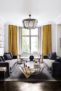 Bright mustard-yellow curtains anchor this grey and white modern living room in a Victorian house designed by Shalini Misra. White walls and herringbone wooden floors provide a clean canvas against which the intricate lines of the pendant lamp and coffee table stand out. The open-plan space is also furnished with a pair of B&B Italia sofas and 'Rita' chairs by Martino Gamper. Living Room Design Ideas