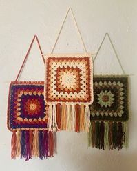 These beautiful handmade crochet wall hanging pieces are great for decorating any space. The design features a large granny square with a flower at the center, and tassels to accent the colors. Add this wall hanging décor to any space to add a handcrafted eclectic vibe. Perfect for a gallery wall as well. Dimensions: 10in by 10in main square 6in tassels 9in hanging string from wooden dowel to top of triangle *disclaimer: Colors may very due to lighting. The piece may need reshaping upon arrival