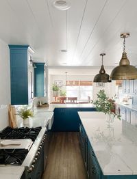 Blue kitchen cabinets. Natural light. Brass pendant lighting. Kitchen island. White shiplap ceilings.