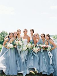 Dusty blue and pink for dusty blue wedding colors for 2025, dusty blue bridesmaid dresses, white bridal gown, white and pink flowers and greenery of bouquets and reception centerpieces, dusty blue wedding tablecloth, dusty blue wedding cake with pink flower décor, dusty blue wedding ring box.