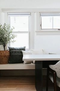 Custom built in seating design by Jenny Murphy rests under a bright and airy modern window for the dining area.