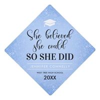 Inspirational graduation cap topper featuring a pastel blue background that can be changed to any color, pale blue glitter, a mortarboard, the grad quote "she believed she could so she did", the graduates name, and the class year.