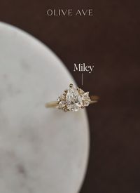 14K Yellow Gold | Miley features a gorgeous pear center stone with clusters of pear and round stones set in a basket on a half round shank.