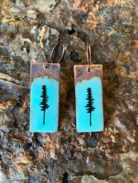 Enameled Copper Pine Tree Earrings. I hand-cut these from a sheet of recycled copper. I then sift vitreous glass enamel onto the piece and torch fire at a high temperature to achieve the color. These have a rustic look and each earring is very unique.