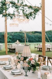 Are you a classic bride planning your dream wedding?  We loved designing and planning this timeless wedding with luxury wedding lights in the beautiful wedding tent.  The crystal chandeliers with greenery was a custom lighting installation we added to the reception space.  We added luxury lights to the wedding tables with small gold lamps, scalloped table lamps, and candles.  Follow @lit_charleston for more classic wedding light ideas!  Wedding Planner: @classicplanninganddesignco | Venue: Cotton Hall in Beaufort, South Carolina | Photo credit: Lindsey Morgan Photography