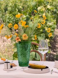 Step into a realm of gastronomic delight amidst the vineyards, as Lalique crystal harmonizes with Alison Thirion's artistic ceramics. Satin textures, translucent elements, and vibrant green hues blend together in flawless balance.