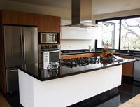 Kitchen | Contemporary, white and wood cabinets, black granite countertops, stove on center island forest view, natural wood floor, black granite floor and black metal frame windows | Mexico City #HuacalEstudio #InteriorDesign #Mexico #MadeInMexico #Styling #Decor #Kitchen