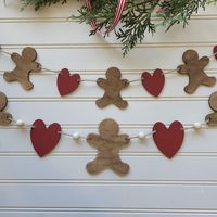 Gingerbread Garland **Turnaround time is currently 2-3 weeks** Deck the halls with this charming Gingerbread Garland! Made of durable wood, this festive garland features adorable gingerbread men and hearts that will add a touch of whimsy to your holiday decor. Hang it on your wall or drape it on your tree for a sweet and festive touch. Each garland comes with 6 gingerbread men and 5 hearts. Available in 2 different sizes: Mini garland gingerbread men measure 3"  Large garland gingerbread men measure 4" tall (includes beads)