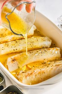 Baked cod infused with lemony garlic butter is the perfect entrèe when you're craving a healthy & light meal! We love these oven-baked cod fillets, served on a layer of fresh lemon slices! #bakedcod #spendwithpennies #bakedcod #recipe