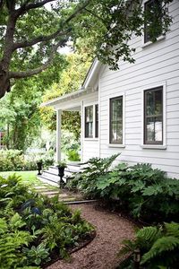 Side garden of a white farmhouse. Love the layout of this and the lush greenery. Makes it so much more refined #Landscape #OutdoorSpace #CurbAppeal #LandscapeDesign