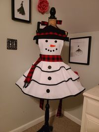 "This adorable Snowman Retro Style Hostess Apron will get you in the festive mood and delight your guests. Full circle skirt, fully lined bodice. Buttons used for Eyes, Mouth and Front Buttons on Skirt. Material: 100% Cotton Fabric/Bias Piping Trim: Poly/Cotton Measurements: Across Bodice (Hat Brim): 15\" Neck Ties: 33\" Waist Ties/Sashes: 40\" each Skirt Length: 15 1/2\" Top of Bodice to Bottom of Skirt: 30\" Fits Sizes S/M/L Best Care Instructions: Hand Wash Only, Line Dry, Iron as Needed. Pet