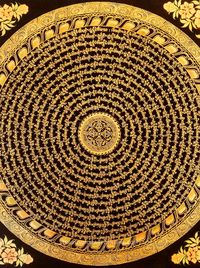 The powerful Buddhist symbol of the vajra at the center of this gold mandala surrounded by the mantra of the Bodhisattva of compassion in Sanskrit.