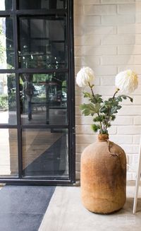 Modern Commercial Space | Big clay jar with flowers, exposed white brick and black metal frame glass door | Mexico City #HuacalEstudio #EyeWear #CoolStore #MadeInMexico