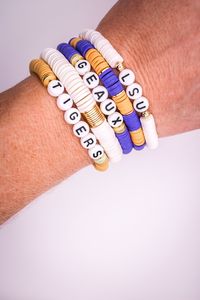 "Show Stopper Stack! Show your school spirit with these stunning LSU themed bracelets.  Handmade with Heishi beads and gold-filled spacer round beads and discs  🌵This listing is for FOUR Bracelets (option to add the white band with gold discs)      1. White band with \"LSU\"       2. Gold & Purple alternating band with gold discs      3. Purple band with \"GEAUX\"       4. Gold band with \"TIGERS\"       5. Option to add white band with gold discs (select second option for five bracelets)