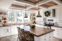 Transitional Farmhouse Kitchen with Butcher Block Countertops We loved this cozy atmosphere in this kitchen with white shaker cabinets, butcher block countertops, a custom range hood, gray chairs, and a dark wood floor. vintage pendants hanged from wooden ceiling fitted with white ceiling beams.