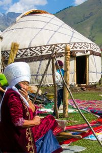 Kyrgyz woman on her mobile phone while weaving at the World Nomad Games in Kyrgyzstan.