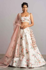 In an exquisite ode to superior craftsmanship, our white raw silk “Sukoon” lehenga is adorned with a floral design. It is accompanied by a sleeveless blouse and a peach organza zardozi embroidered bordered dupatta.