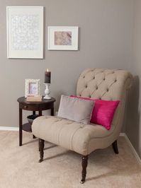 See a traditional gray bedroom sitting area with a neutral tufted chair accented by throw pillows.