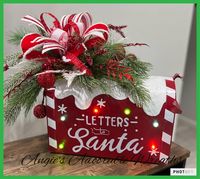 This Santa mailbox is metal with battery operated lights   Decorated with beautiful Christmas foliage and beautiful wired ribbon bow Requires two AA batteries Approximately 17 inches long by 14 x 13 This product ships from Texas from a pet and smoke free home We look cute on any entry door table or placed underneath your Christmas tree rotating plant not included