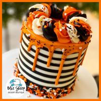 White and black striped buttercream cake with orange chocolate drip & fancy Halloween sprinkles!