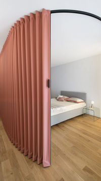 In this project, a large, curved textile folding wall embraces the master bedroom and transforms the space in few, simple gestures. When opened at various points, the door shapes the room in multiple solutions, creating ever-changing paths and dynamics. 