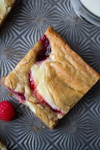 A recipe for a cheesecake and raspberry jam-swirled blondie bar. Chewy, sweet and delicious!