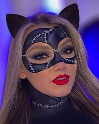 This elegant and mysterious Catwoman makeup showcases a sleek, stitched mask that exudes sophistication and intrigue. The mask is meticulously painted with black and silver tones, creating a textured look that mimics stitched leather. The bold red lips add a striking contrast, enhancing the overall allure of the costume. The eye makeup is smoky and seductive, with long, dramatic lashes that draw attention to the eyes. This look is ideal for those with hooded eyes, as it accentuates the upper part of the face and adds depth. The subtle yet impactful details make this makeup a perfect choice for Halloween or any costume event, offering a balance of easy application and stunning results.   Photo credit by: @hayleyshanksmakeup