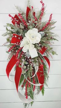 Welcome the holiday season in style with this glamorous Christmas wreath, perfect for adorning your front door or any space in your home. Crafted with the utmost care and attention to detail, this wreath is a true masterpiece of seasonal decor. Our Christmas wreath features lifelike snowy magnolia blooms, glittery eucalyptus, frosted red berries, and iced cedar and pine, creating a winter wonderland right at your doorstep.