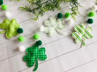 Dress up your home with some lucky St Patricks decor! This clover garland is perfect to dress up your mantle or hang in a doorway, even cute for a St Patricks themed Baby Shower or birthday!   Details: *Garland comes in various lengths  * Materials used are fabric clovers, felt balls and string *Each clover is 4x4" *Felt balls are 1 inch thick