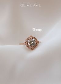 14K Rose Gold | Bloom features a cushion center stone with a stunning channel prong halo and milgrain detail set in a cathedral setting on a half round shank.