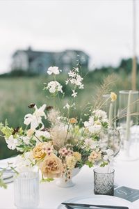 Delicate, airy and organic wedding reception table flowers in shades of white, green, sand and pale peach featuring honey dijon garden roses, white tiger lilies, scabiosa, cherry caramel phlox, nicotiana, chocolate cosmos, white cloud larkspur & seaside grasses.