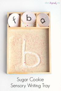 Learning to write letters with a sugar cookie sensory tray! This is such a fun way to use your senses to learn the alphabet. This would make a great Christmas sensory writing activity!