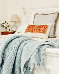 Decorating a bed with a blue blanket and pillows can enhance the overall home decor.