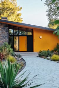 Mid century modern house facade in mustard yellow color with charred accents. Check out all of these vibrant exterior color combinations of these charming mid-century modern houses that make them real masterpieces.