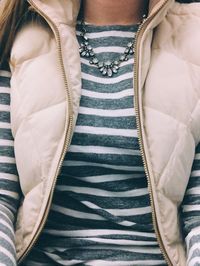 Gray and white striped shirt, cream-colored vest, and statement necklace.