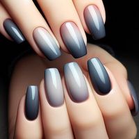 A beautiful gradient design that transitions from a deep charcoal grey at the cuticle to a light, misty grey at the tips. The ombré effect is seamless, creating a smooth transition between the shades. The nails are finished with a glossy top coat, giving the design a subtle shine that enhances the gradient effect.