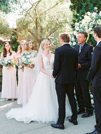 Bride smiling during ceremony. Circular ceremony arch with silver dollar eucalyptus, white dahlias and roses. Estancia La Jolla wedding shot on film by Cavin Elizabeth Photography