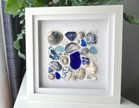 Coastal Collection (No.2)  Scottish Sea Glass, Pottery & Shells Artwork Blue Colour Theme The creative process behind this piece is to showcase the beautiful discoveries I make while beachcombing along the Scottish coastlines, with pieces of sea glass, sea pottery and shells, in a variety of colours, shapes and textures. Shells include; blue cockle, grey limpets, grey flat periwinkle, grey top shell, mussel shells, and a pelican's foot (bottom right corner). In the bottom right corner, there is