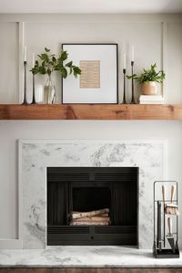 For a timeless mantel setup, we framed a page of sheet music and flanked it with some simple greenery and candlesticks. The marble fireplace surround gives the room a modern detail and a little extra texture. #modernstyledecor